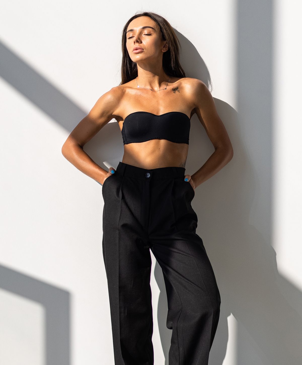 Model in black outfit against a white wall.