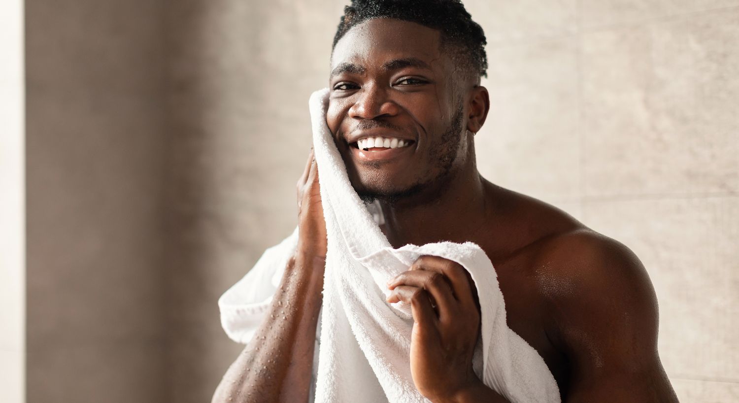 Smiling man drying his face with a towel.