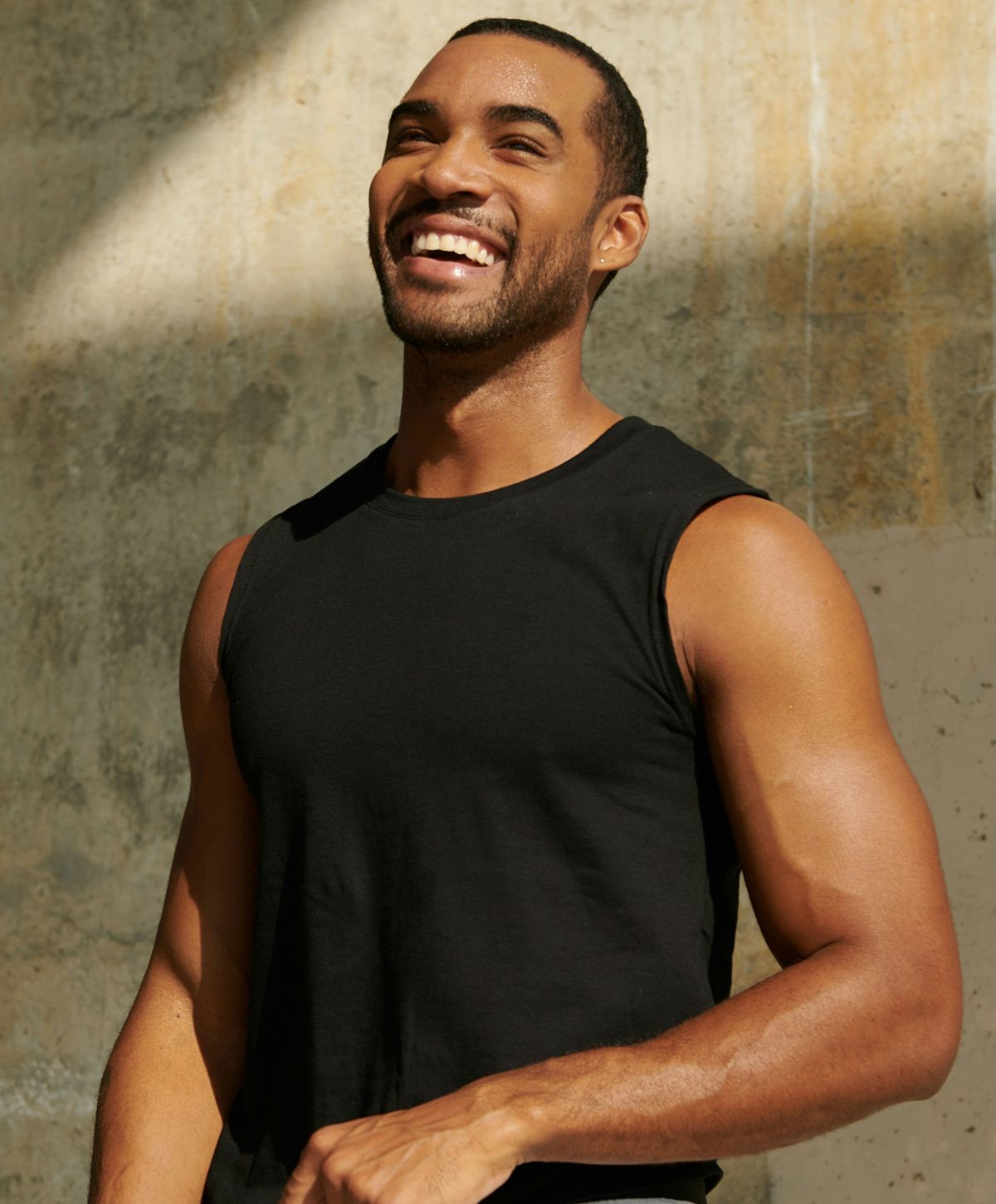 Smiling man in sleeveless black shirt outdoors.